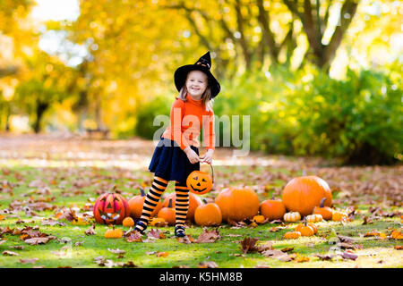 I bambini con la zucca di Halloween. bambina in costume da strega e hat giocando in autunno park. bambino di halloween dolcetto o scherzetto. kid trucco o trattare. Foto Stock