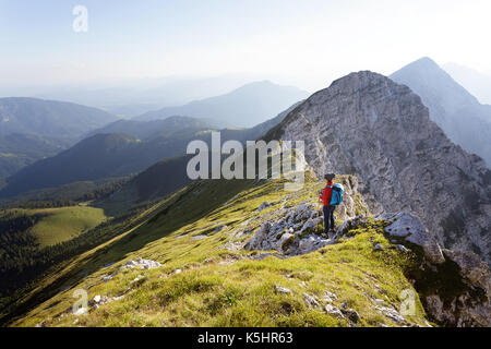 Donna in piedi su una montagna e godendo la vista sulle montagne. Kladivo, Karavanke, Slovenia. Foto Stock