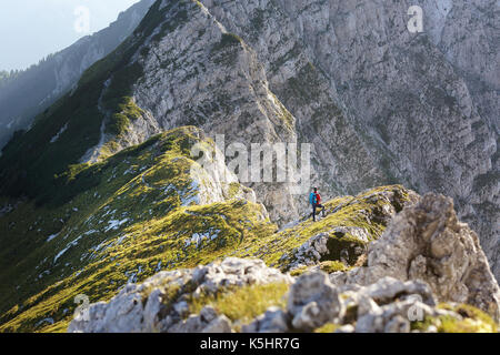 Woman in Red jacket, con bastoni per escursioni e passeggiate zaino fino a un punto di vista su Kladivo, Karavanke, Slovenia. Foto Stock