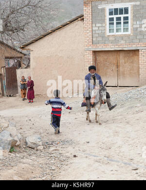 Il vecchio uomo che cavalca un asino in un villaggio di montagna Foto Stock
