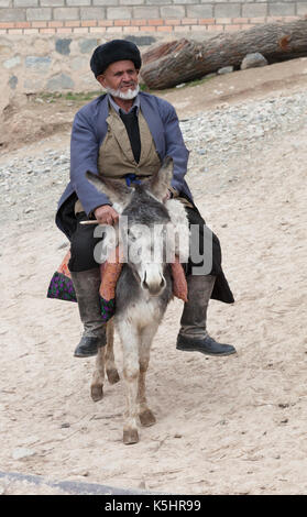 Il vecchio uomo che cavalca un asino in un villaggio di montagna Foto Stock