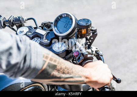 Fresco guardando i tatuaggi sui bracci del motociclista su custom made stile scrambler cafe racer Foto Stock