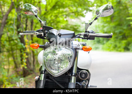 Immagine di un motociclo parcheggiato su una strada di campagna in una foresta Foto Stock