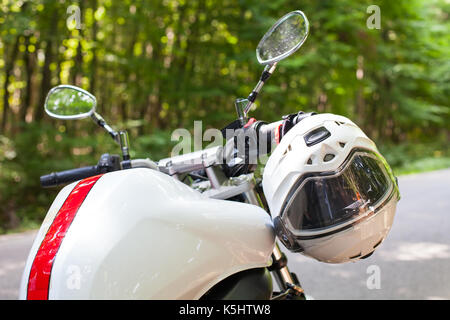 Immagine di un motociclo parcheggiato su una strada di campagna in una foresta Foto Stock