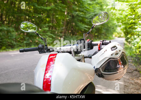 Immagine di un motociclo parcheggiato su una strada di campagna in una foresta Foto Stock