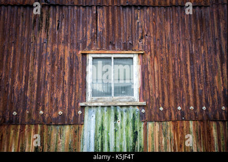 Rusty ferro corrugato edificio, magazzino con finestra. Foto Stock