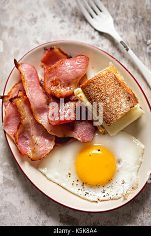 Uova fritte, pancetta e baguette con formaggio mozzarella sandwich. piastra di prima colazione Foto Stock