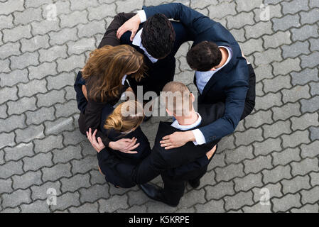 Angolo di alta vista di imprenditori in piedi in huddle Foto Stock