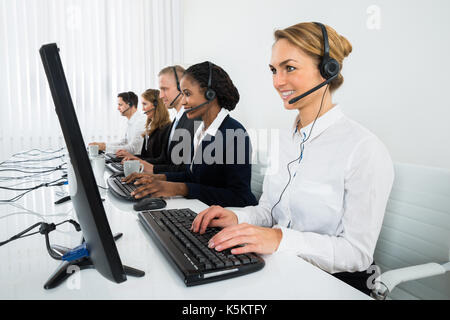 Operatori call center in una fila lavorando sul computer in ufficio Foto Stock