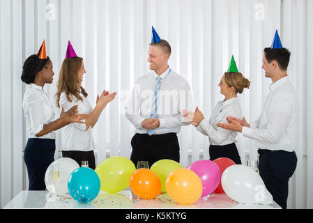 Un gruppo di imprenditori ad applaudire al Manager durante il Party In ufficio Foto Stock