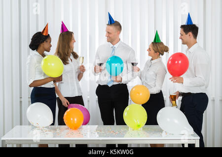 Team di happy businessman avente una bottiglia di champagne in ufficio Foto Stock