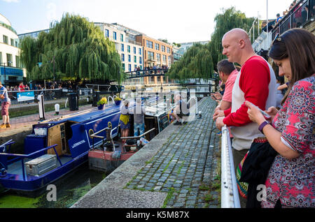 Gli spettatori di guardare un paio di strette boas passano attraverso hampstead road lock sul Regent's Canal di Camden Town, Londra. Foto Stock