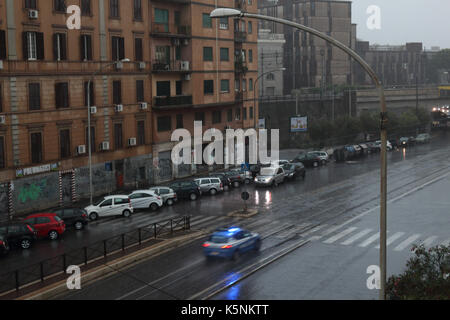 Macchine parcheggiate e una macchina della polizia sotto la pioggia sulla via Prenestina. Roma, Italia. Foto Stock