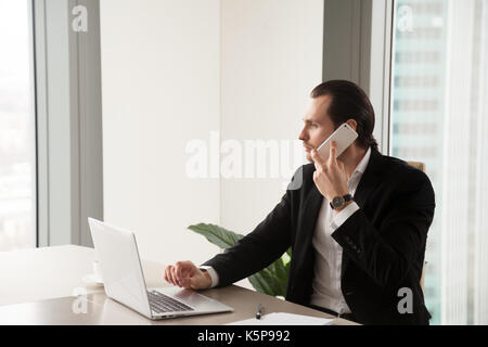 Grave giovane imprenditore in office effettuare chiamate telefoniche. Foto Stock