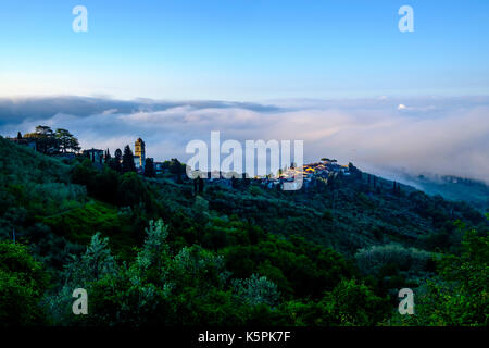 Le case del borgo sono fuori della nebbia nella valle val di Pescia al di sotto di Foto Stock