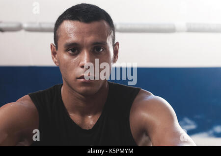 Ritratto di sudate latino-americano boxer maschio guardando con fiducia della fotocamera dopo aver lavorato in palestra di inscatolamento Foto Stock