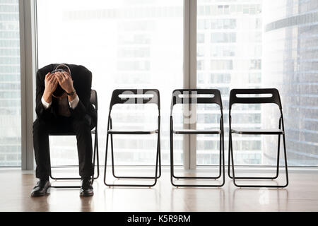 Sottolineato sconvolto imprenditore seduti su una sedia, ricevuto cattive notizie. Foto Stock