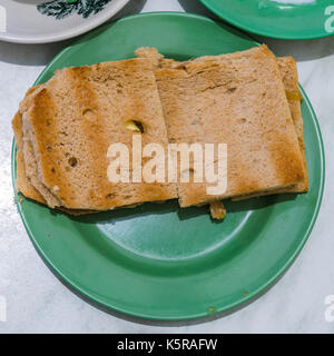 Tradizionale colazione singapore chiamato kaya toast, pane con marmellata di noce di cocco e semi-uova sode, il fuoco selettivo, il frattale sulla tazza è generico pri Foto Stock