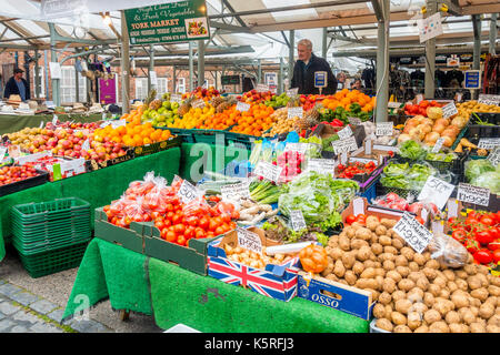 Uomo e servire a frutta e verdura in stallo il caos Mercato nel centro di York Inghilterra Foto Stock