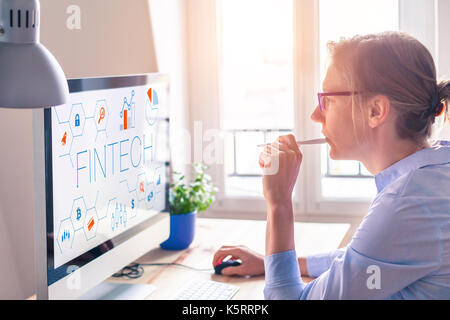 Concetto di fintech sullo schermo del computer con interfaccia moderna e innovativa di grafici, femmina persona business in ufficio Foto Stock