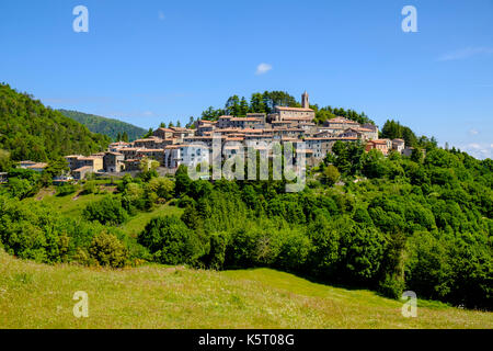 Le case in pietra del piccolo borgo si trova sulla cima di una collina e circondato da alberi Foto Stock