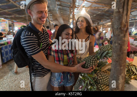 Gruppo di turisti scelgono di Ananas tropicale sulla strada del mercato in Thailandia i giovani acquisto di frutta fresca Foto Stock