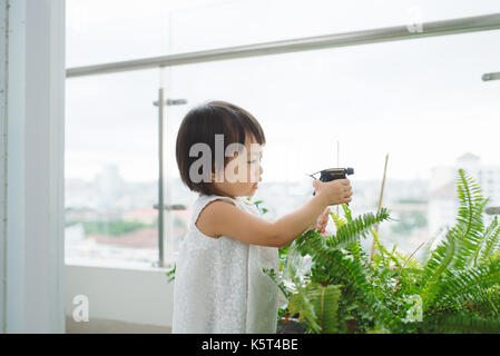 Bambino di prendersi cura di piante. carino bambina prima di irrigazione fiori di primavera Foto Stock