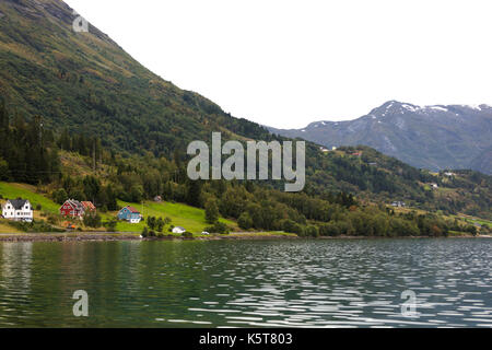 Paesaggio norvegese ai piedi di un lago con lo sfondo della foresta e le montagne nevose Foto Stock