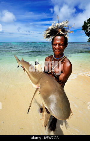 Tribù folk korafe, l uomo con il tipico tapa indumenti di corteccia di albero contiene un captive blacktip Shark Reef (Carcharhinus Foto Stock