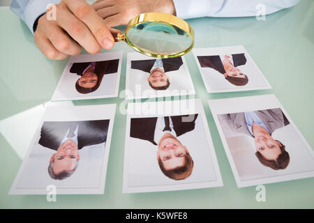Close-up di una persona a mano candidato con la fotografia e la lente di ingrandimento Foto Stock