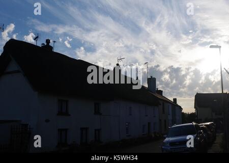 Stagliano cottage tetti contro un effimero estate del cielo della sera di textured cumulus nubi. Villaggio di morchard bisphop, metà devon, Regno Unito. 2017. Foto Stock