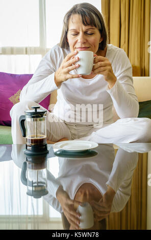 Donna matura è godendo del caffè fresco la mattina Foto Stock