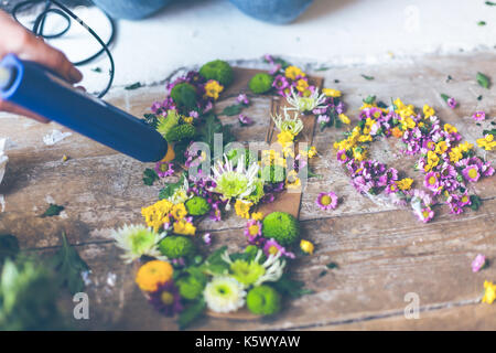 Fioraio effettuare decorazioni di fiori con lettere e colla. in interni luce naturale shot con piccole profondità di campo Foto Stock