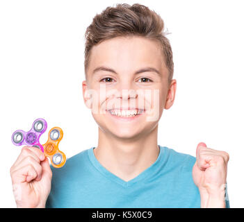 Young Teen boy holding agitano: popolare giocattolo spinner - close up ritratto. sorridenti bambino che gioca con un dispositivo a rotazione vorticosa, isolato su sfondo bianco. Foto Stock