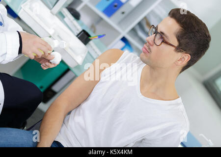 Medico la vaccinazione di giovane uomo in ospedale Foto Stock