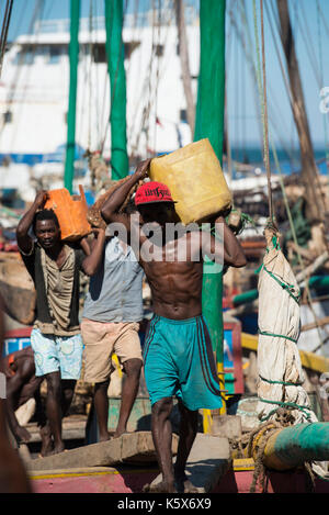 Gli uomini off-caricamento del carico da dhow nel vecchio porto Dhow, Mahajanga, Madagascar Foto Stock