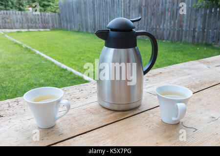 Thermos con due tazze in un giardino Foto Stock