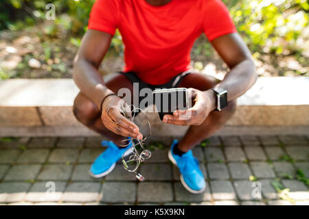 Irriconoscibile runner con smart phone, ascoltando musica. Foto Stock