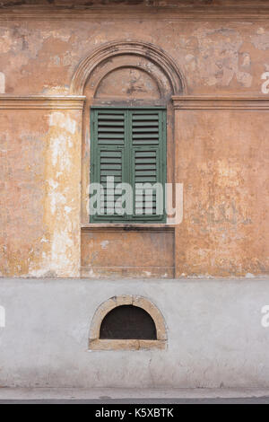 Vecchia città europea edificio con chiusura finestra verde persiane e piccola finestra semicircolare sotto la grande finestra Foto Stock