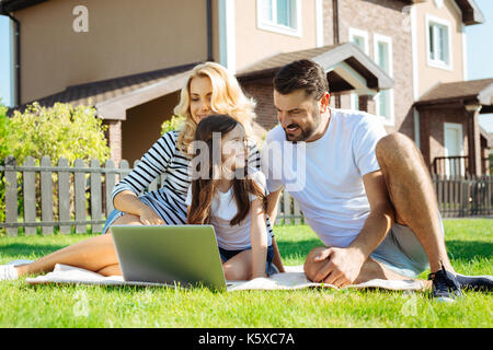 Genitori felici guardando cartoni animati con la loro figlia in cantiere Foto Stock