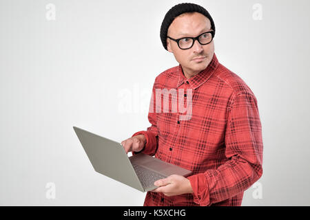 Uomo caucasico con il computer portatile utilizzando il telecomando e guardando a parte. Foto Stock