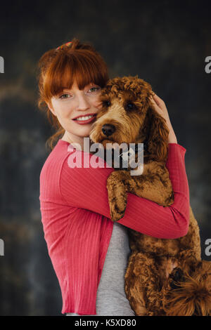 Donna in posa con il suo cane nelle sue braccia. Foto Stock