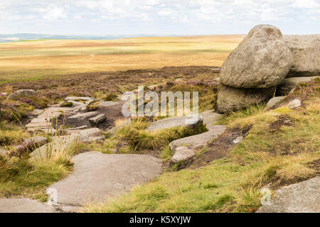 Vista dal bordo stanage derbyshire. cercando di rocce in primo piano su per la brughiera e poi su per il cielo nuvoloso. Foto Stock