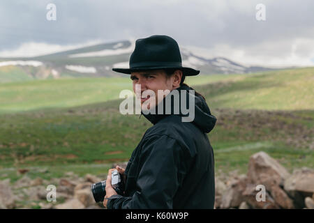 Il fotografo può contenere una fotocamera nelle mani delle montagne armene. Foto Stock