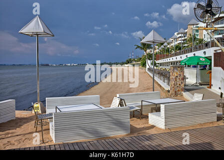 Area ristorante del resort sulla spiaggia Thailandese con tavoli e sedie che si affacciano sull'oceano. Pattaya, Thailandia, Sud-Est Asiatico Foto Stock