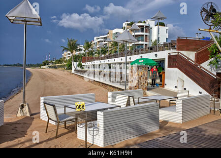 Area ristorante del resort sulla spiaggia Thailandese con tavoli e sedie che si affacciano sull'oceano. Pattaya, Thailandia, Sud-Est Asiatico Foto Stock