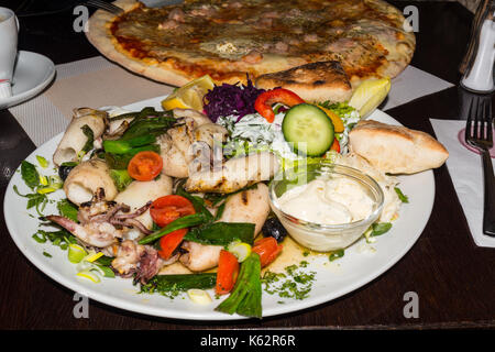 Calamari alla griglia con contorni, pane e insalata. Foto Stock