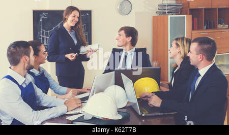 Professionisti positivo con i caschi e laptop avente riuniti in ambienti interni Foto Stock