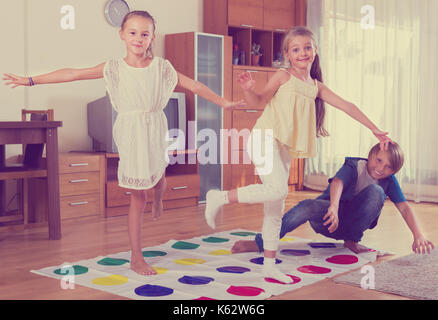 Gruppo di bambini felici giocando a twister in interni Foto Stock