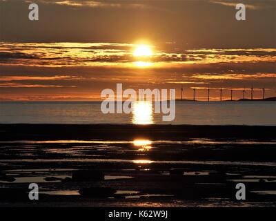 Tramonto dietro Robin Rigg off-shore wind farm, maryport, Cumbria Regno Unito Foto Stock